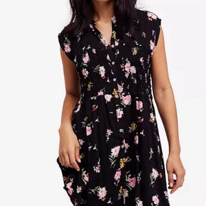 May include: A black short-sleeved dress with a floral print in shades of pink, yellow, and green. The dress has a button-up front and a cinched waist.
