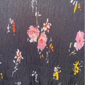 May include: Black fabric with a white and pink floral pattern. The fabric has a textured, gathered look.