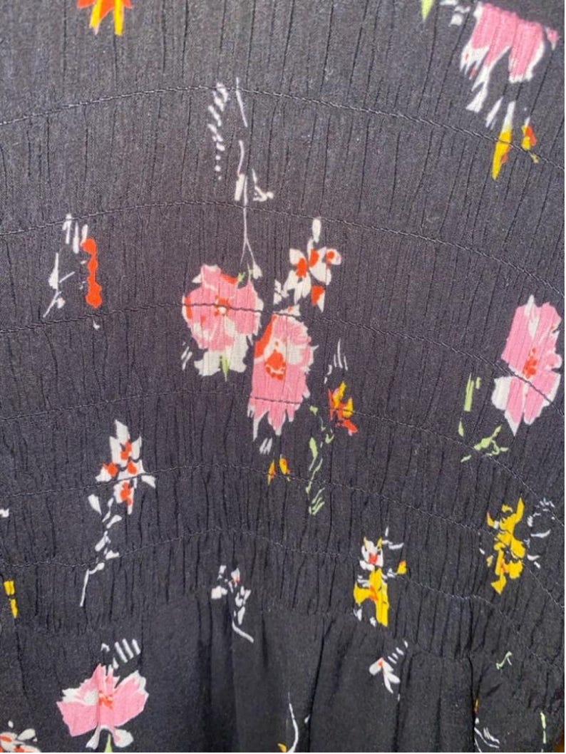 May include: Black fabric with a white and pink floral pattern. The fabric has a textured, gathered look.