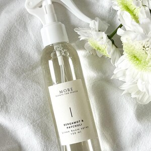 Peut inclure: Une bouteille en verre transparente avec une buse de pulv&eacute;risation blanche et une &eacute;tiquette blanche. L'&eacute;tiquette indique "MORE SCENTS FOR SPACES" et "BERGAMOT & PATCHULI Linen Room spray 150 ml".