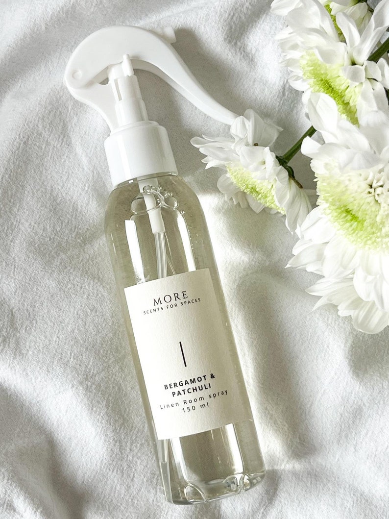 Peut inclure: Une bouteille en verre transparente avec une buse de pulv&eacute;risation blanche et une &eacute;tiquette blanche. L'&eacute;tiquette indique "MORE SCENTS FOR SPACES" et "BERGAMOT & PATCHULI Linen Room spray 150 ml".
