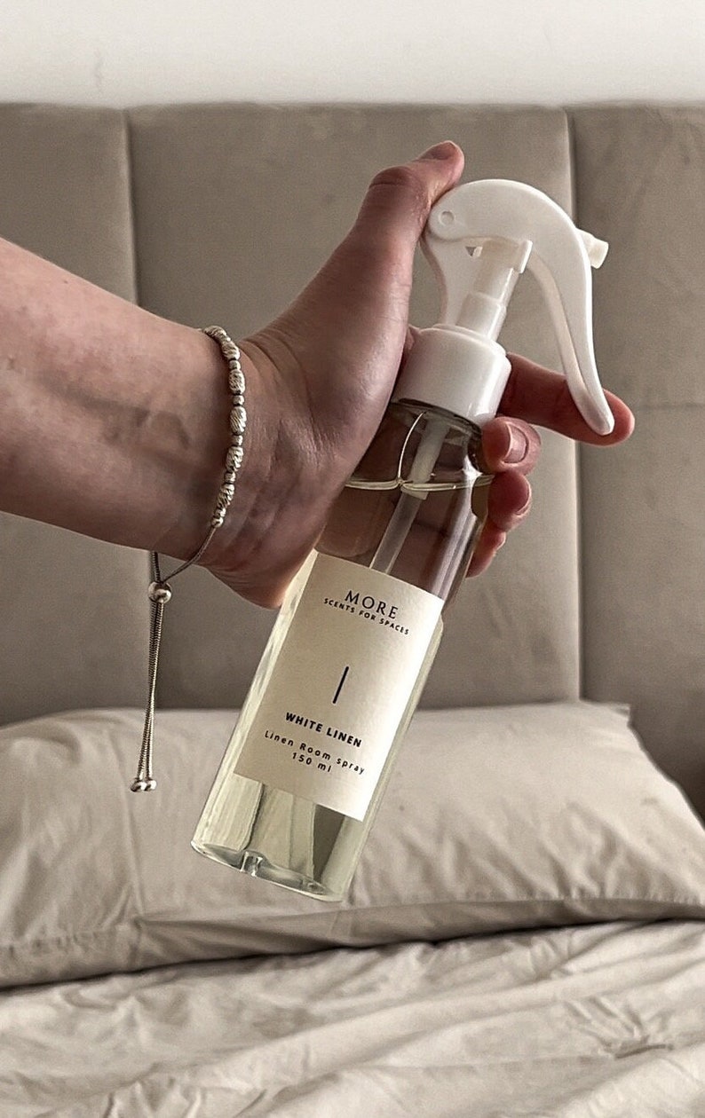 Peut inclure: Une bouteille en verre transparente avec une buse de pulv&eacute;risation blanche et une &eacute;tiquette blanche. L'&eacute;tiquette indique "MORE SCENTS FOR SPACES" et "WHITE LINEN Linen Room Spray 150 ml".