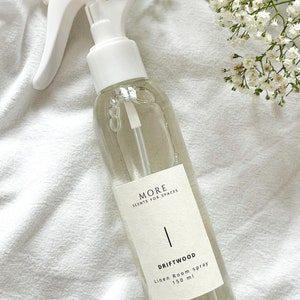 Peut inclure: Une bouteille en verre transparente avec une buse de pulv&eacute;risation blanche et une &eacute;tiquette blanche. L'&eacute;tiquette indique "MORE SCENTS FOR SPACES" et "DRIFTWOOD Linen Room spray 150 ml".