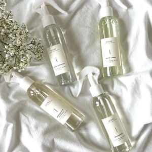 Peut inclure: Quatre flacons pulv&eacute;risateurs en verre transparent avec des embouts pulv&eacute;risateurs blancs et des &eacute;tiquettes. Les &eacute;tiquettes portent le texte "MORE SCENTS FOR SPACES" et les noms des parfums : "Island Hibiscus", "White Linen", "Bergamot & Basil", et "Driftwood".