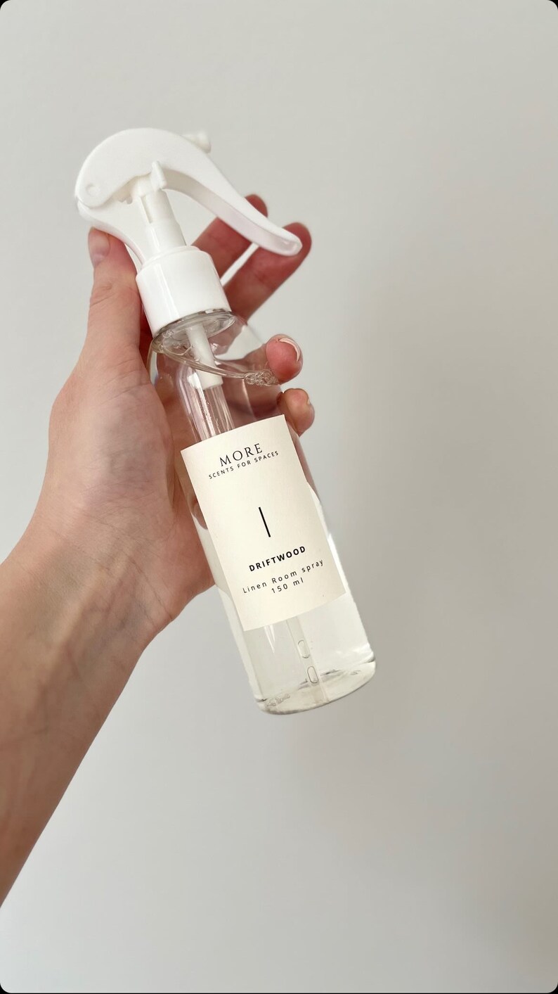 Peut inclure: Un flacon pulv&eacute;risateur en plastique blanc contenant un liquide clair. L'&eacute;tiquette indique "MORE SCENTS FOR SPACES" et "DRIFTWOOD Linen Room Spray 150 ml".