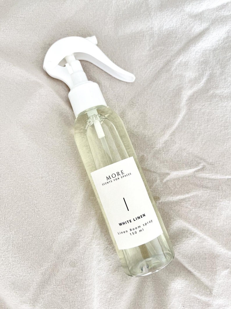 Peut inclure: Une bouteille en verre transparente avec une buse de pulv&eacute;risation blanche remplie d'un liquide clair. La bouteille porte une &eacute;tiquette blanche avec le texte "MORE SCENTS FOR SPACES" et "WHITE LINEN Linen Room Spray 150 ml".