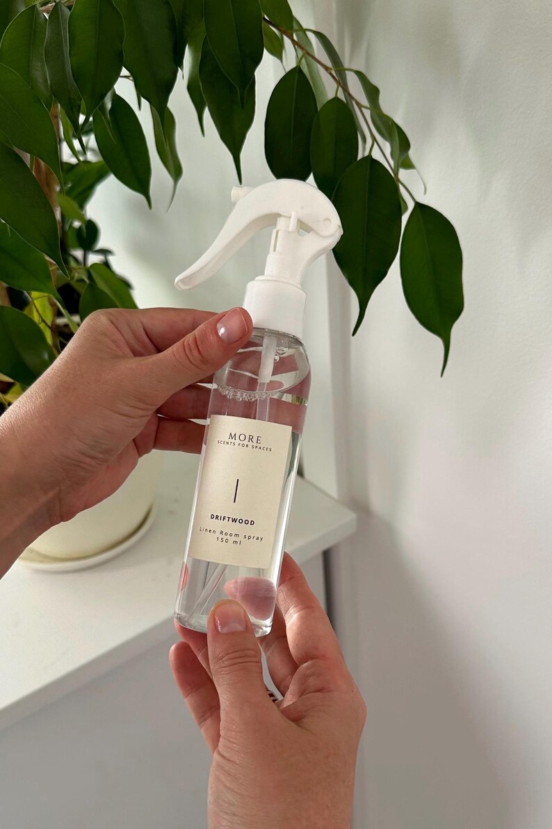 Peut inclure: Une bouteille en verre transparente avec une buse de pulv&eacute;risation blanche et une &eacute;tiquette blanche. L'&eacute;tiquette indique "MORE SCENTS FOR SPACES" et "DRIFTWOOD Linen Room Spray 150 ml".
