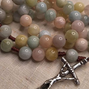 Peut inclure: Un chapelet de perles bleu clair, rose et jaune avec un crucifix en argent.