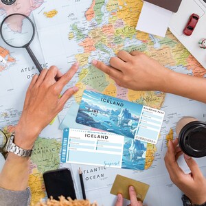 May include: Two people are planning a trip to Iceland. They are looking at a world map and a boarding pass for a flight to Iceland. The boarding pass is blue and white and has the words "Boarding Pass" and "Iceland" on it. There is a cup of coffee and a credit card on the table.
