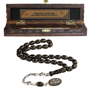 Peut inclure: Un chapelet de prière noir et or avec un gland argenté et une boîte en bois. La boîte est ornée d'une sculpture et d'une plaque avec le texte "Benimle olduktan sonra asla pişman olmazsın benim olduktan sonra asla pişman olmazsın".