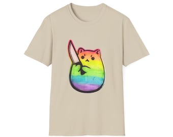 Op de afbeelding: Een beige t-shirt met een regenboogkat die een mes vasthoudt. De kat is zwart omlijnd en heeft een wit gezicht.