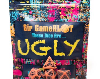 May include: A set of orange dice with black numbering, arranged in front of a bag. The bag has a colorful splatter design and the text "Sir GameALOT These Dice Are... UGLY". The dice are for tabletop games.