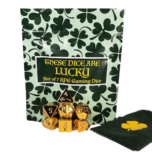 May include: A set of seven gold-colored metal RPG gaming dice arranged in front of a light green pouch featuring a dark green clover pattern. The pouch label reads "THESE DICE ARE LUCKY Set of 7 RPG Gaming Dice." A black drawstring bag with a gold clover.