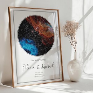 May include: A framed rectangular wall art print featuring a circular star map with orange and blue nebula clouds. The text reads: The Night We Met, Oliver & Rachael, May 23rd, 2026, AMSTERDAM, NL, 52.520° N, 13.405° E. The print has a thin black border.