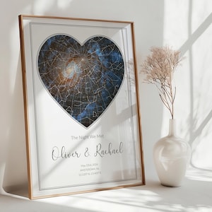May include: A framed star map print featuring a heart-shaped celestial design with constellations against a dark blue nebula background. The text reads The Night We Met, Oliver & Rachael, May 23rd, 2026, AMSTERDAM, NL, 52.520° N, 13.405° E.