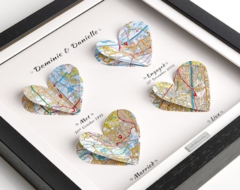 May include: A framed map art piece with four heart-shaped maps representing different stages of a relationship: "Met", "Engaged", "Married", and "Live". The dates of each stage are included below the heart-shaped maps.