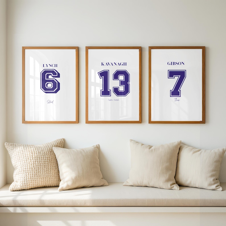 May include: Three framed wall art prints with wooden frames. Each print features a name, a large jersey-style number in dark blue, and a smaller script name below. The prints display the names Lynch 6, Kavanagh 13, and Gibson 7.