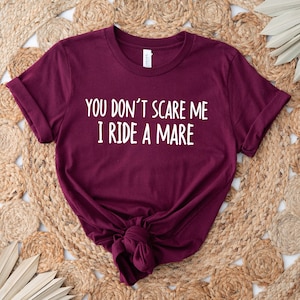 May include: Burgundy t-shirt with white text that reads "You don't scare me I ride a mare".