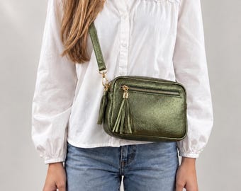 May include: A metallic olive green rectangular crossbody bag with a gold-tone zipper closure, a matching leather tassel pull, and an adjustable shoulder strap. The bag features a front zippered pocket and a smooth, shimmering finish.