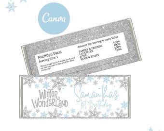 May include: A silver and blue Winter Wonderland themed chocolate bar wrapper with snowflakes and the text "Winter Wonderland Samantha's 1st Birthday". The wrapper also includes a nutrition facts label with the text "Nutrition Facts Serving Size: 1" and "Amount Per Serving % Daily Value Family & Friends 100% Laughter 100% Love 100% Hugs & Kisses 100%"