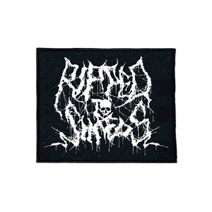 May include: Black and white embroidered patch with the text "Drowned in the Sun" in a gothic font. The text is surrounded by a dripping, splatter design.