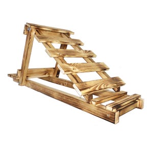Peut inclure: Une planche inclinée en bois avec cinq marches, en bois naturel avec une finition rustique brûlée. La planche est inclinée vers le haut et possède une plate-forme plate en haut.