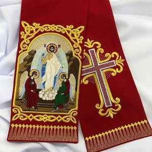 May include: Red fabric stole with gold embroidery featuring a religious icon of Jesus Christ with two angels, and a cross on the right side.
