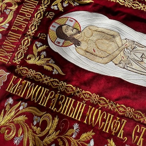 May include: A red embroidered banner with gold and white thread. The banner features a depiction of Jesus Christ and the text "SHRZ I ROHAMH RO ГРОБИ БЛАГООБРАЗНЫЙ НОСИФЪ, CE IG НОВЋ, ПОКРЫКТ ОКРЫВЪ ПОЛОЖ".