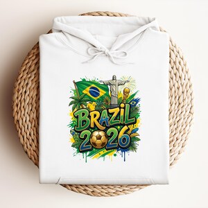 White hoodie with "Brazil 2026" text, soccer ball, and Brazilian flag.