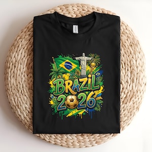 Black t-shirt with "Brazil 2026" text, soccer ball, flag, and Christ the Redeemer statue.