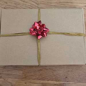 May include: A brown cardboard box with a red bow tied on top. The box is wrapped with twine.