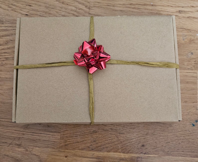 May include: A brown cardboard box with a red bow tied on top. The box is wrapped with twine.