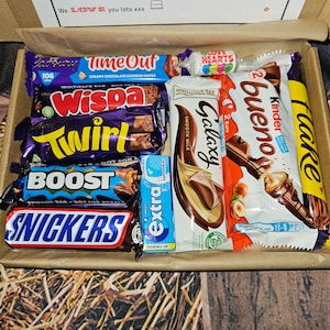 May include: A box filled with various chocolate bars, including Twirl, Wispa, Galaxy, Kinder Bueno, and Snickers. The box also contains a small bag of Love Hearts candy.