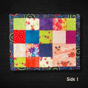 May include: A colorful patchwork quilt with a black border featuring a swirl design. The quilt is composed of various fabric squares in shades of red, blue, green, purple, and pink. One square has the text "If it involves pants or a bra, it's not happening."