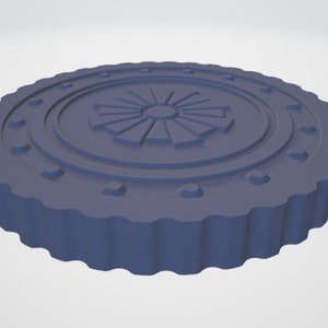 May include: A round, blue, decorative object with a raised, circular design in the center. The design features a sunburst pattern with a central circle.