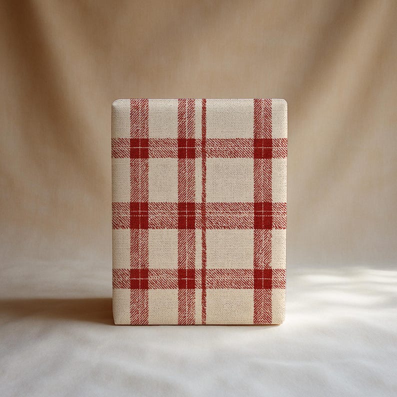 K&ouml;nnte beinhalten: Ein rechteckiger Hocker, bezogen mit cremefarbenem Stoff mit einem roten Karomuster. Das Karomuster bedeckt die gesamte Oberfl&auml;che des Hockers. Der Hintergrund ist ein neutrales Beige. Der Hocker hat eine rechteckige Form.