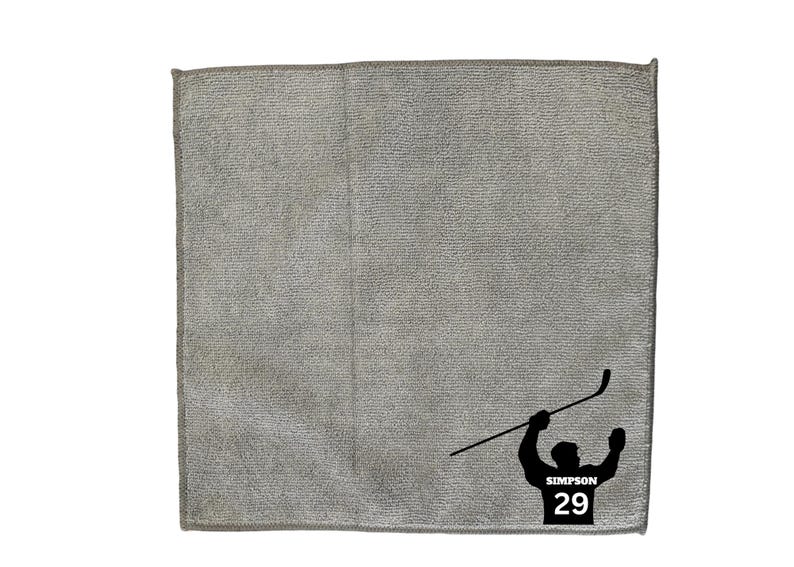 May include: Gray microfiber cleaning cloth with a black silhouette of a hockey player holding a hockey stick and the text "SIMPSON 29".