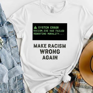 Może przedstawiać: Biały ceramiczny kubek z czarnym uchwytem i napisem "But First, Coffee" pogrubioną czcionką. Kubek jest ustawiony na rozmytym tle, sugerującym przytulne otoczenie.