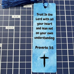 May include: A blue bookmark with a tassel, featuring the text "Trust In the Lord with all your heart and lean not on your own understanding Proverbs 3:5" and a black cross.