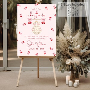 May include: A light pink baby shower sign featuring a cherry pattern, a central illustration of a ruffled baby romper on a hanger, and text reading: She is the cherry on top, Please join us for a baby shower honoring Sophia Williams, July 25, 2pm.