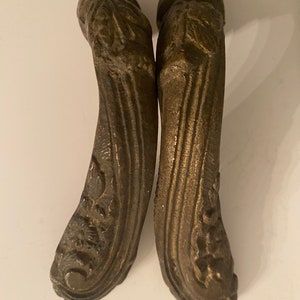 May include: Two ornate, antique-style, brass door handles with a decorative floral design.