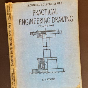 May include: A vintage book titled "Practical Engineering Drawing, Volume Two" with a light blue cover. The cover features technical drawings and text. The book's spine reads "Practical Engineering Drawing" and "English Universities Press Ltd."
