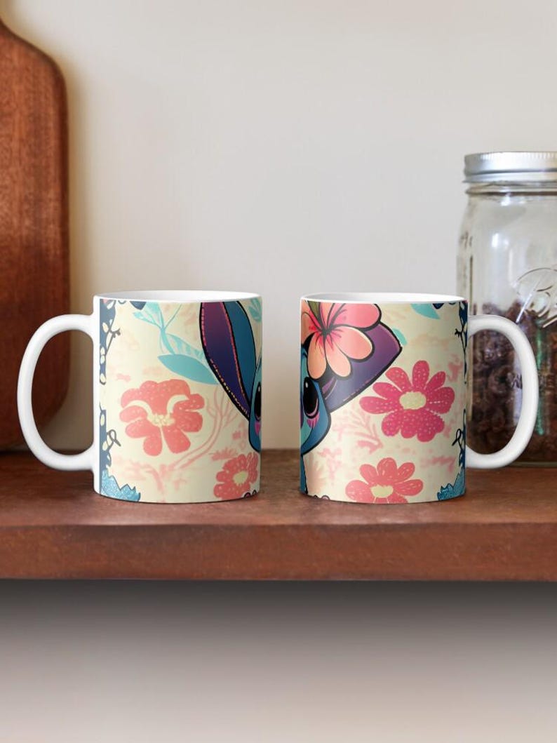 May include: Two white ceramic mugs with a floral pattern and a cartoon character with blue fur and a flower crown. The character is on a light yellow background with pink and blue flowers.