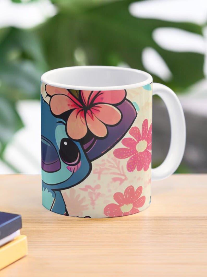May include: A white ceramic mug with a colorful design featuring a cartoon Stitch character with pink flowers. The background is a light pink with a floral pattern.