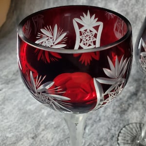 Pode incluir: Duas taças de vinho tinto com um design de cristal cortado. As taças têm um caule e uma base transparentes.
