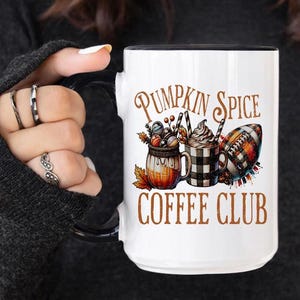 May include: White ceramic coffee mug with a black rim and handle. The mug features a graphic of a pumpkin spice latte, a football, and the text "Pumpkin Spice Coffee Club".