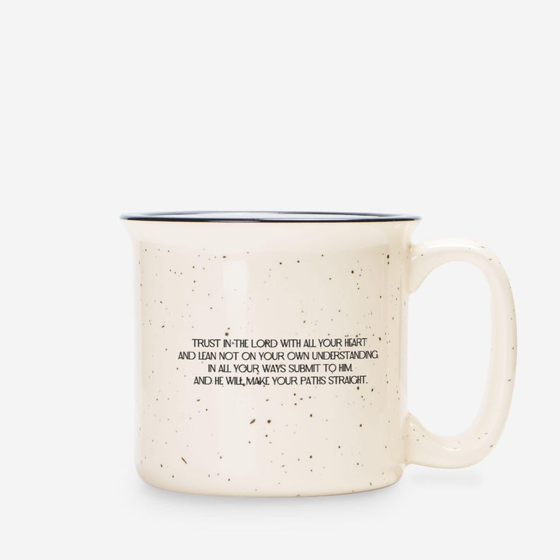 May include: A cream-coloured ceramic mug with a speckled finish and a dark rim. The front features black text that reads: Trust in the Lord with all your heart and lean not on your own understanding; in all your ways submit to him, and he will make your paths straight.