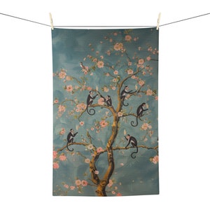 May include: A blue and gold tea towel with a design of a tree with pink blossoms and monkeys holding glasses of champagne.