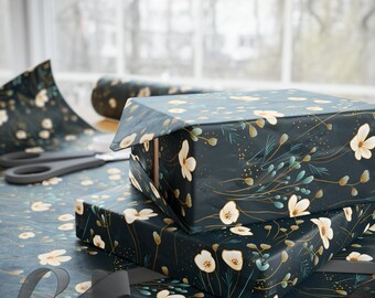 May include: Gift boxes wrapped in dark teal floral patterned paper with white flowers and gold accents. A roll of matching wrapping paper and scissors are visible. A gray ribbon is in the foreground.