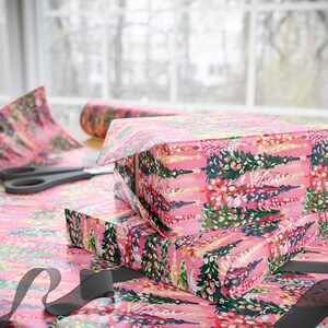Peut inclure: Papier d'emballage rose avec un motif floral repr&eacute;sentant des arbres et des fleurs stylis&eacute;s. Le papier est envelopp&eacute; autour d'une bo&icirc;te cadeau.